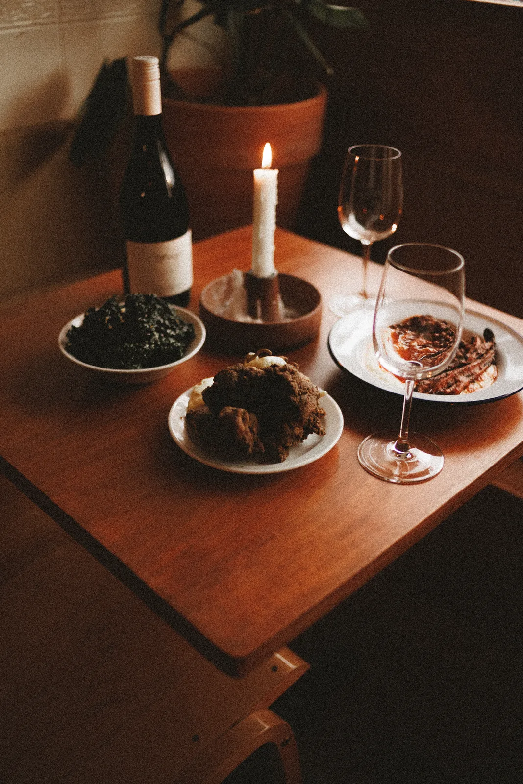 A candlelit table with Mauby dishes and wine