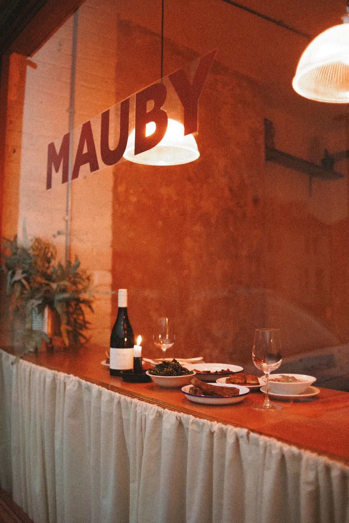 A candlelit table laid with Mauby dishes and wine